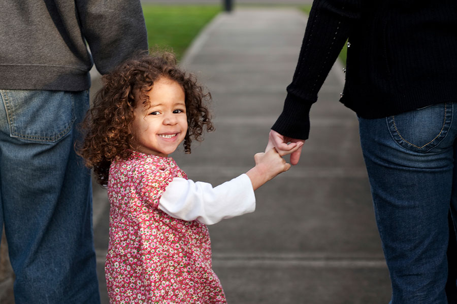 Girl holding hands with mom and dad