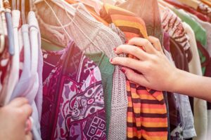 shop to help shopper looking through clothing rack